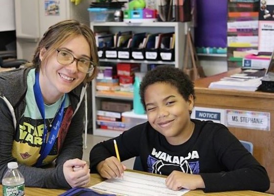 Teacher and student smiling at desk