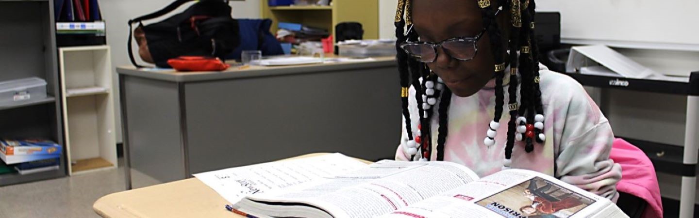 Student reading a textbook at her desk
