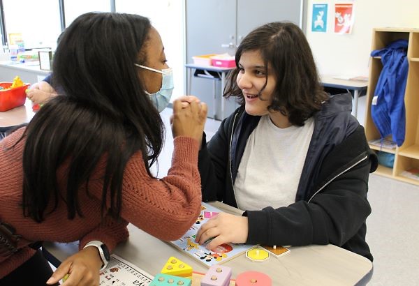 Teacher working with smiling student at her desk