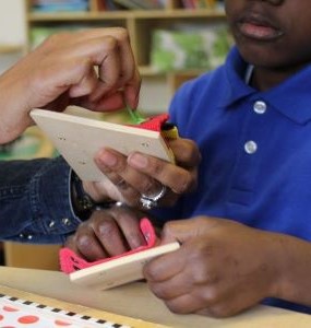 Behavior Technician providing instruction to student at desk