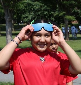 Student smiling at field day holding sunglasses