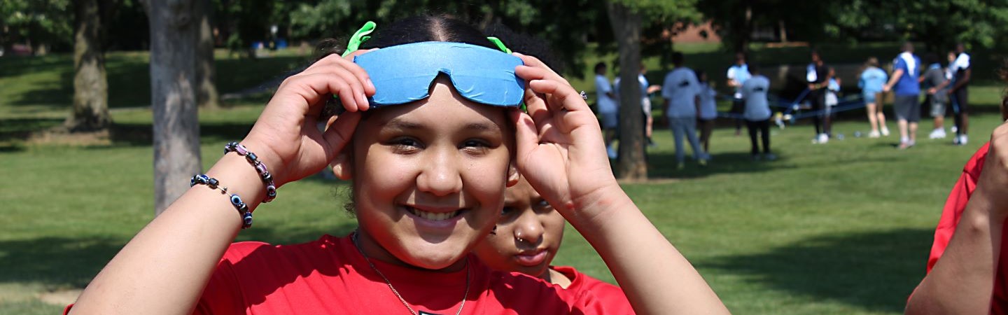 Student smiling while holding sunglasses at field day event