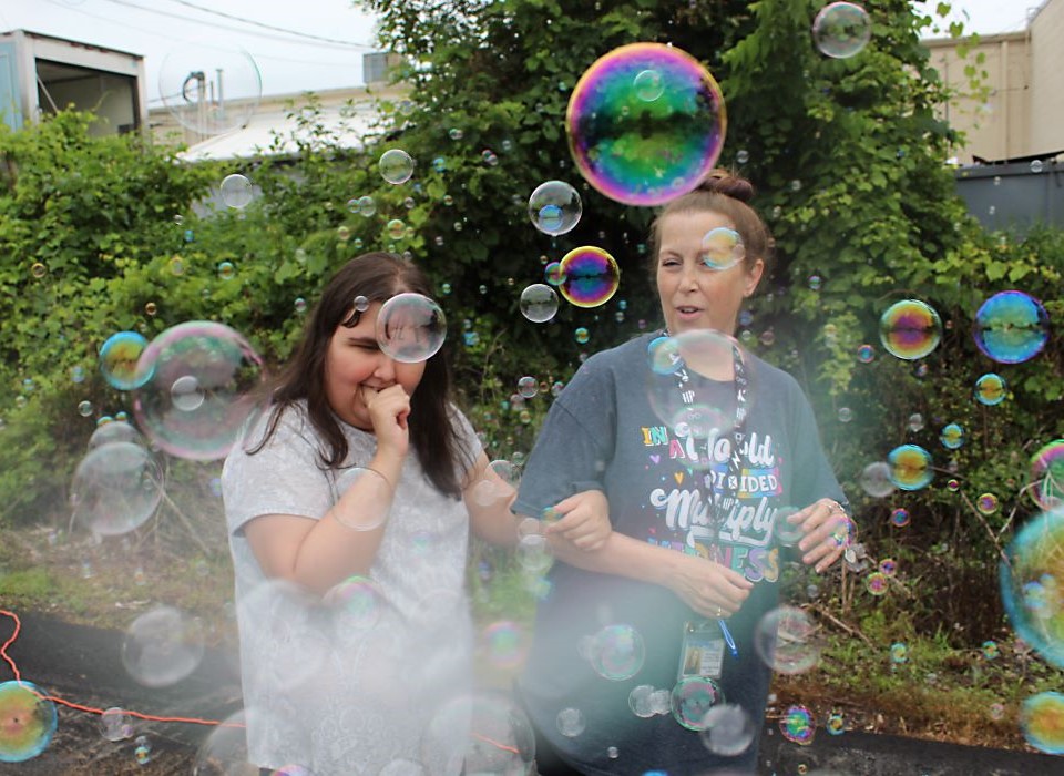 Student and teacher playing with bubbles outside
