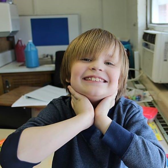 Young student smiling big in his classroom