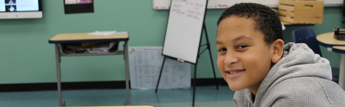 Student smiling while sitting at his desk