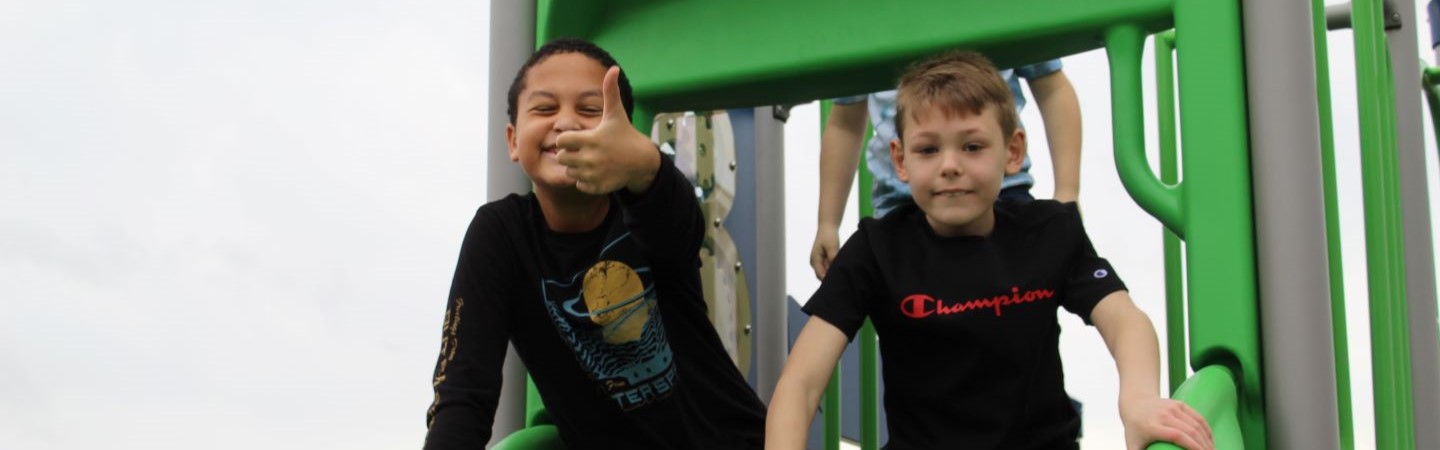 Two students playing on the school playground giving thumbs up