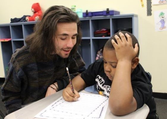 Teacher talking to student as he works on an assignment 