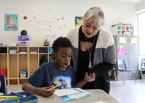 Teacher and student reading together and holding hands