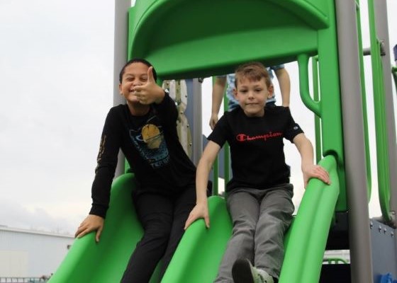 Two students playing on the school playground giving thumbs up
