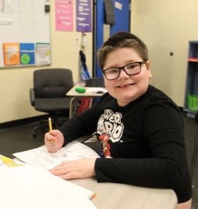 Student smiling working at his desk