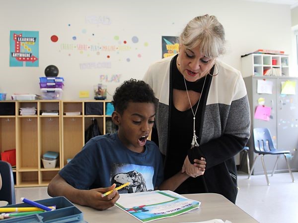 Teacher and student reading together and holding hands