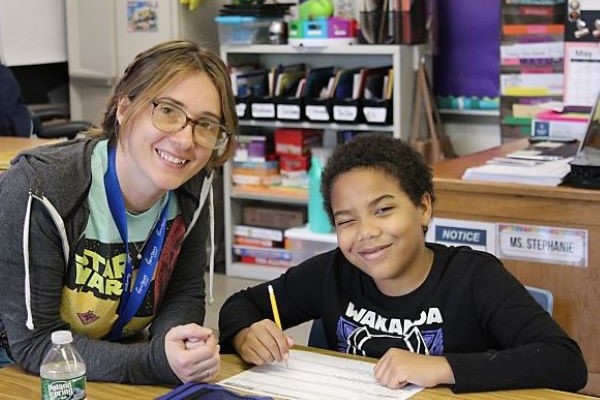 Teacher and student smiling at desk