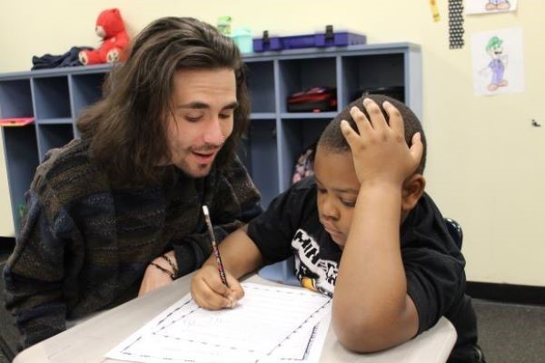 Teacher talking to student as he works on an assignment