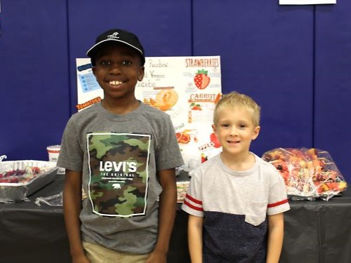 Two students smiling in front of poster