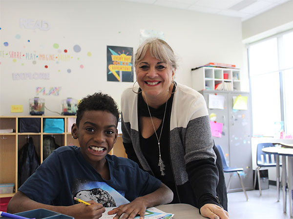 Student and teacher smiling at desk