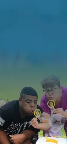 A teacher and student blowing soap bubbles together outdoors during a school activity